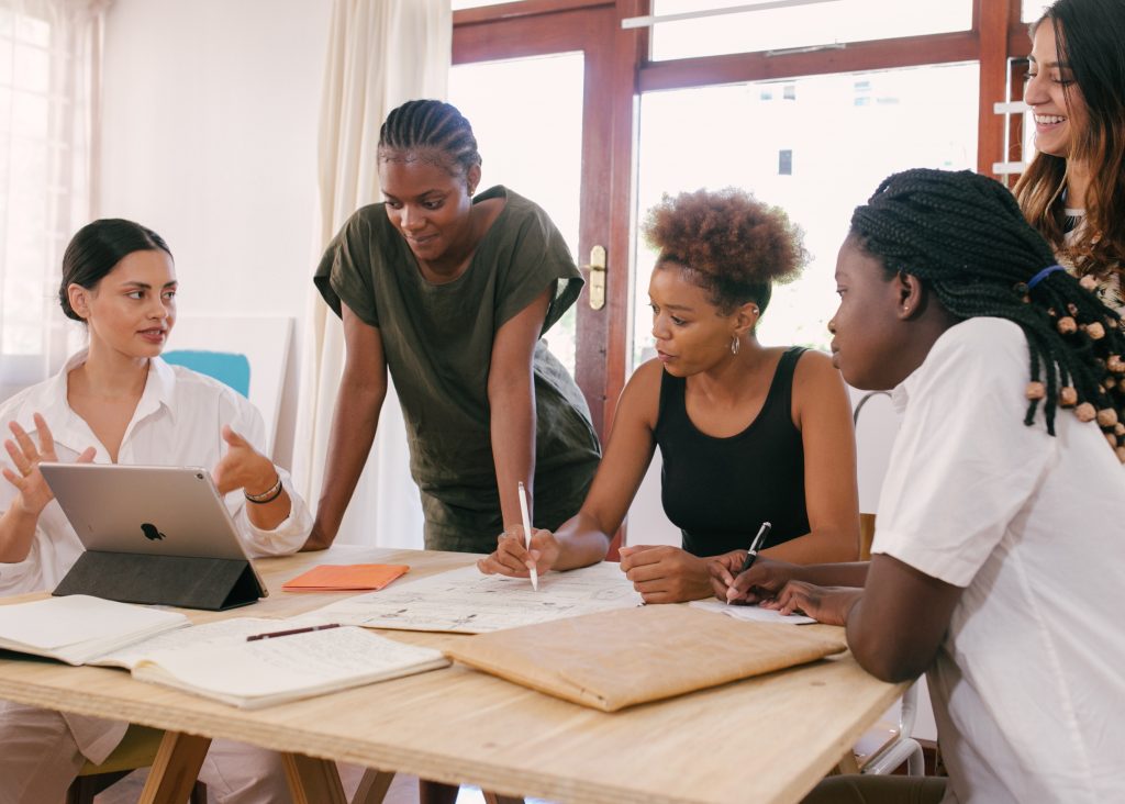 A team gathered around a table reviewing drawings and notes while planning a proposal