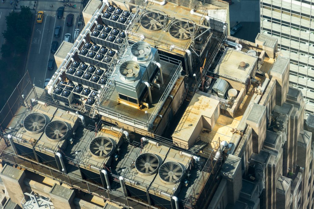 Aerial view of commercial HVAC cooling units and fans on a city rooftop