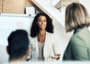 A salesperson presenting to colleagues at a whiteboard